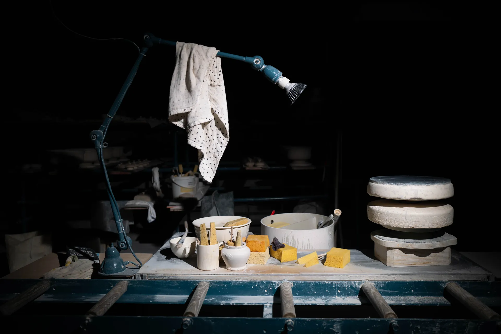 Ouvrier flou en mouvement devant un four à faïence ouvert, chariots de cuisson, pose longue nocturne