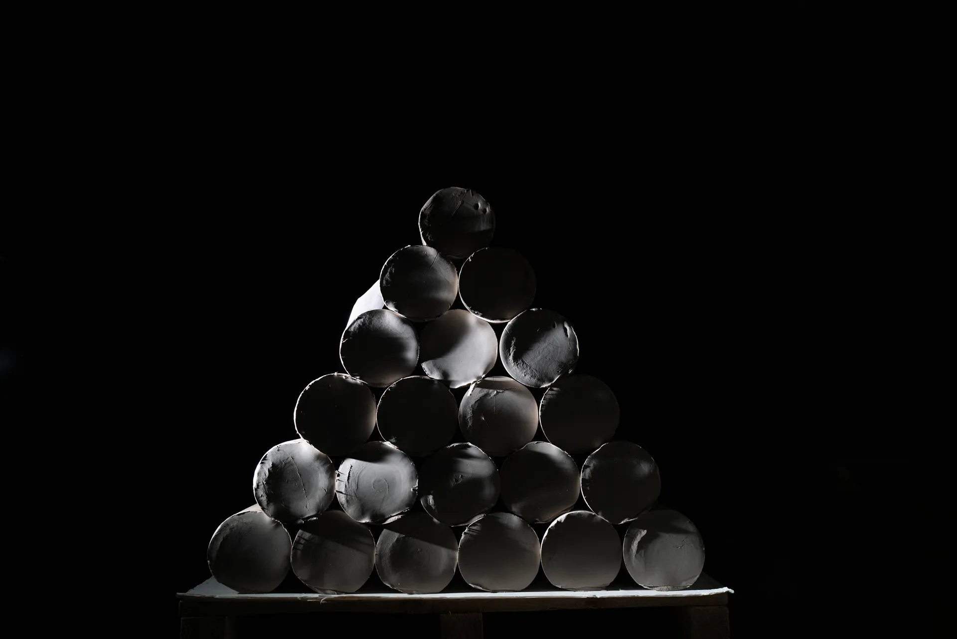 Pichets en faïence blanche alignés sur une étagère dans la pénombre, contre-jour