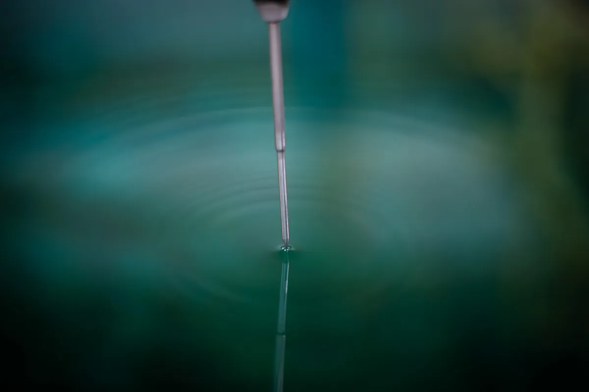 Sonde métallique plongeant dans un liquide turquoise, contrôle qualité en centrale nucléaire