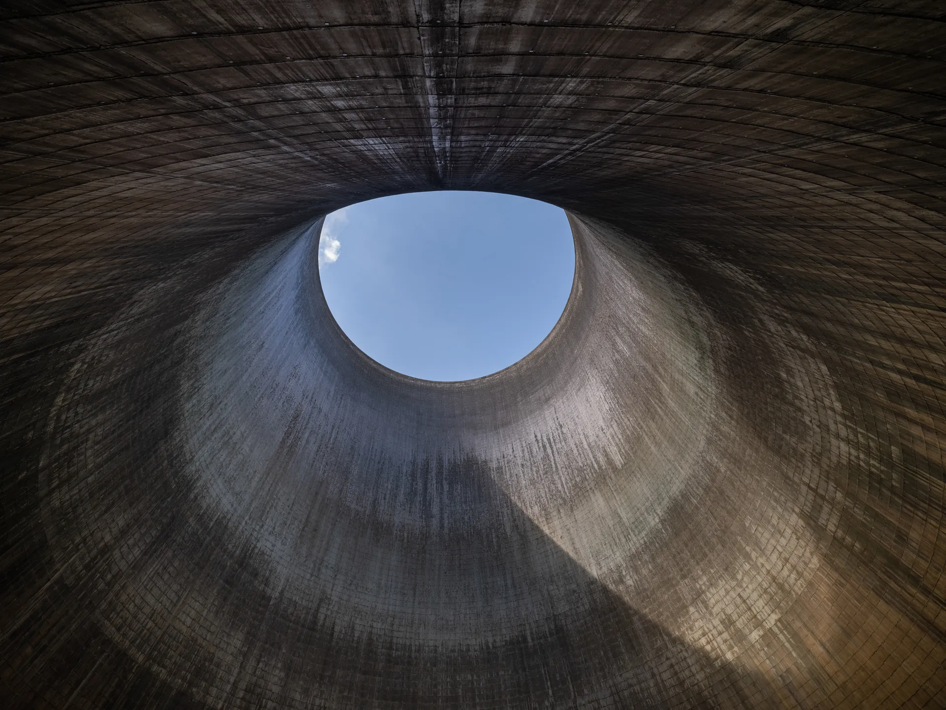 Vue intérieure d'une tour de refroidissement nucléaire, paroi de béton courbe et ouverture vers le ciel