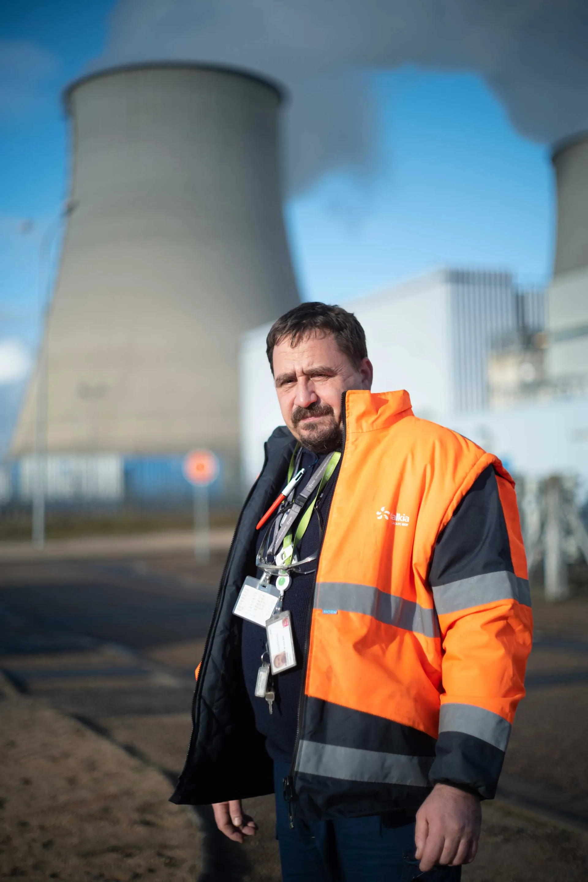 Portrait frontal d'une ouvrière en blouse blanche devant un mur en bois peint vert sombre, Faïencerie de Gien