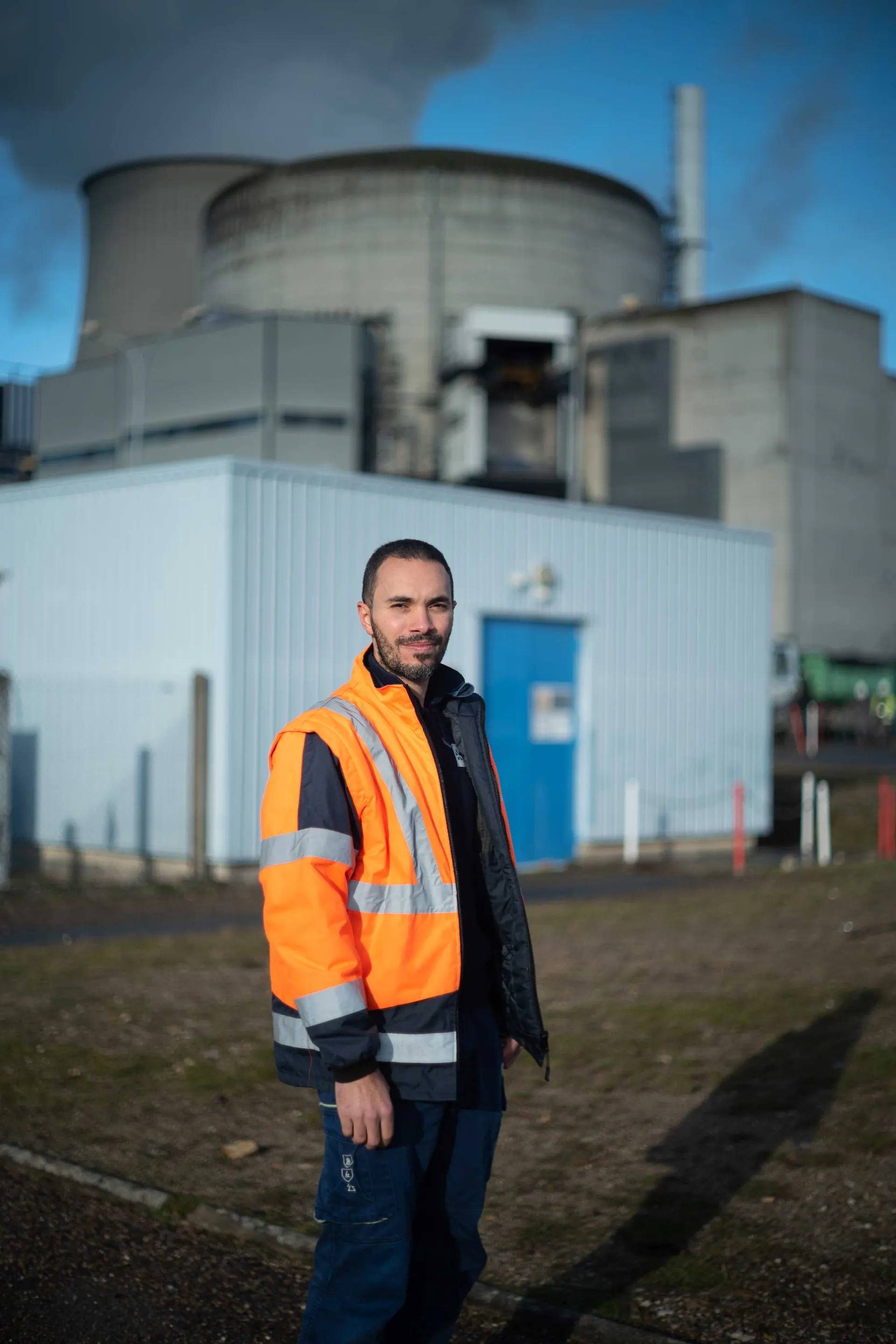 Jeune opératrice en chemise à carreaux dans la salle de commande d'une centrale nucléaire EDF