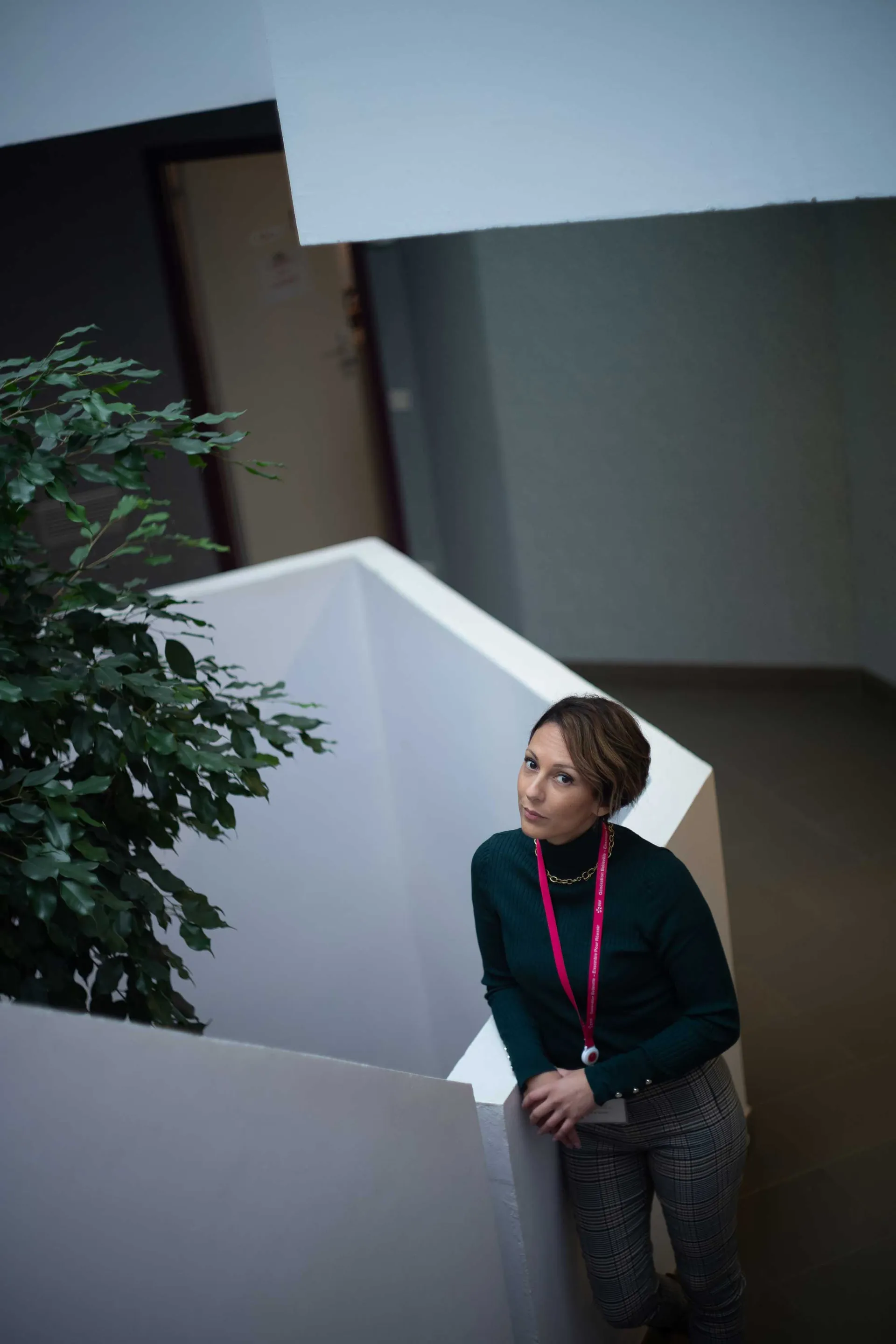 Technicien en gilet haute visibilité orange posant devant la tour de refroidissement d'une centrale nucléaire