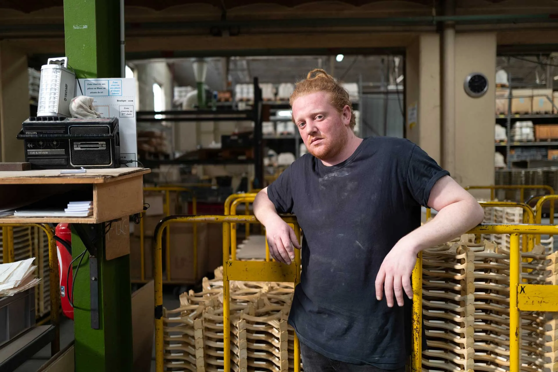 Employée vue en plongée dans une cage d'escalier géométrique, badge EDF rose, regard vers l'objectif
