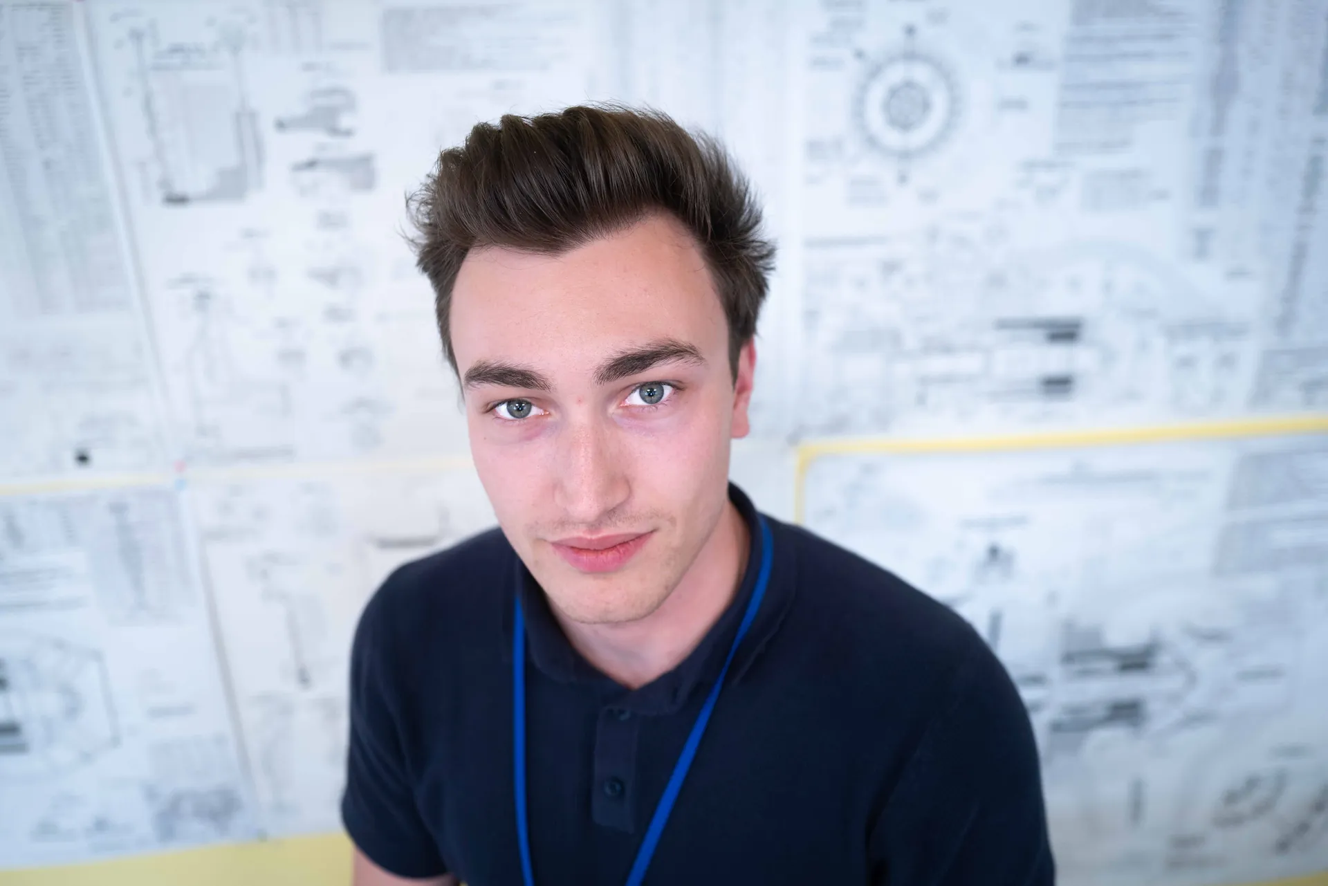 Technicien EDF barbu en casque bleu et combinaison blanche devant des containers sur le site d'une centrale nucléaire