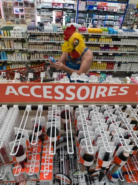 Personnage masqu&eacute; en poule consultant son t&eacute;l&eacute;phone au rayon accessoires