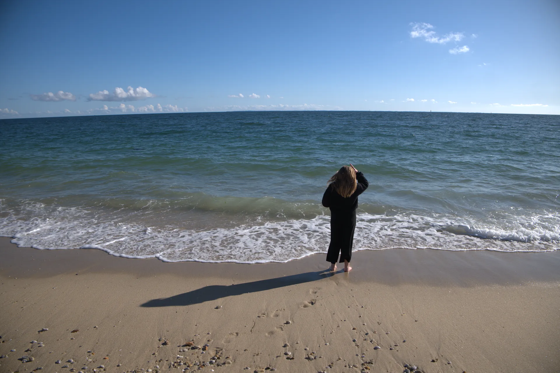 Promontoire rocheux avec croix de pierre, personnes allongées et photographe debout face à la mer