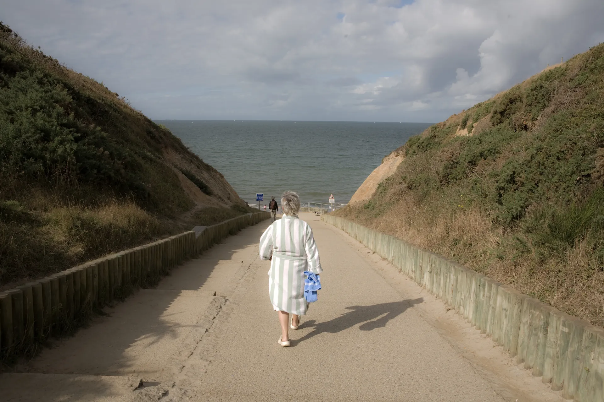 Adulte et enfant debout sur la plage face aux vagues, mouette en vol