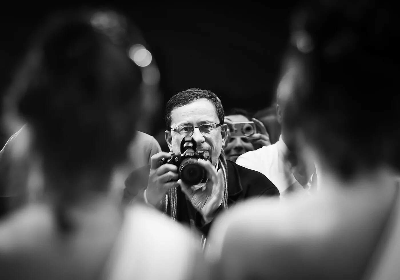 Photographe de presse visant avec son appareil au milieu de la foule lors d'un événement local