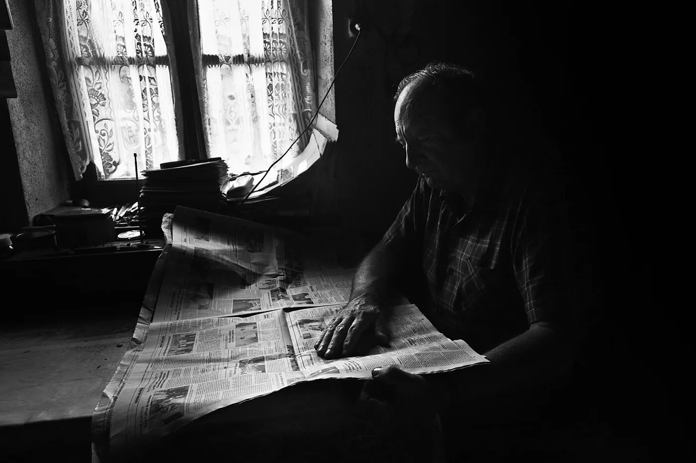 Imprimerie dans l'obscurité, journaux éclairés par un rai de lumière, silhouette d'ouvrier