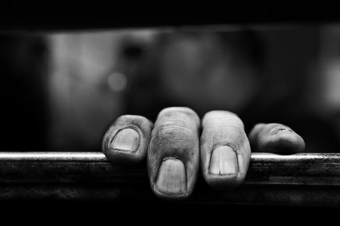 Gros plan sur les doigts tachés d'encre d'un imprimeur agrippant une barre de la rotative