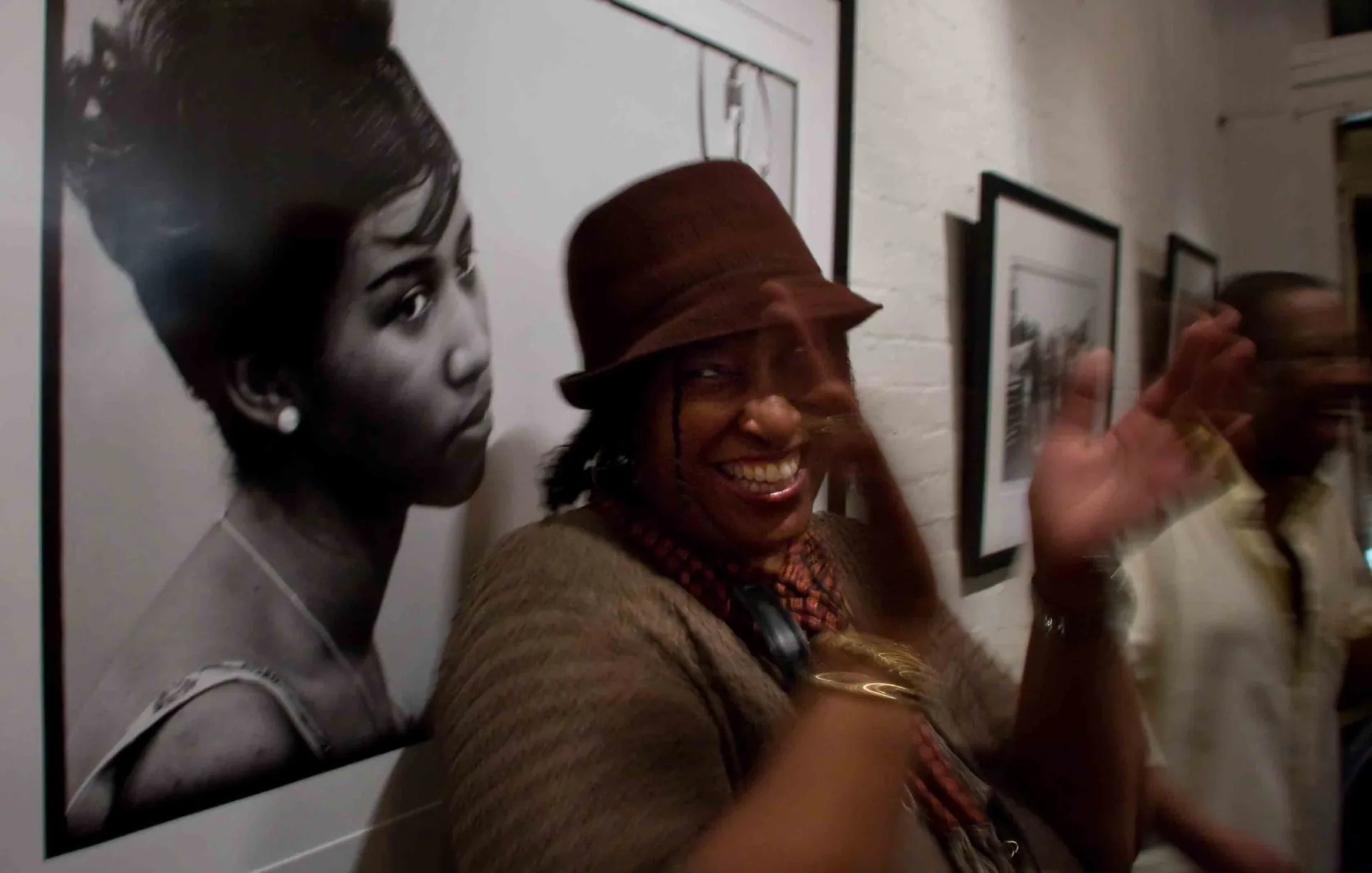 Visiteuse au fedora dans une galerie de photographie, portrait noir et blanc au mur