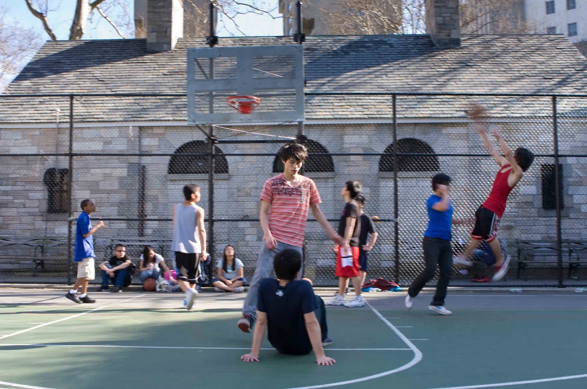 Partie de street basket dans un parc new-yorkais, joueurs et spectateurs