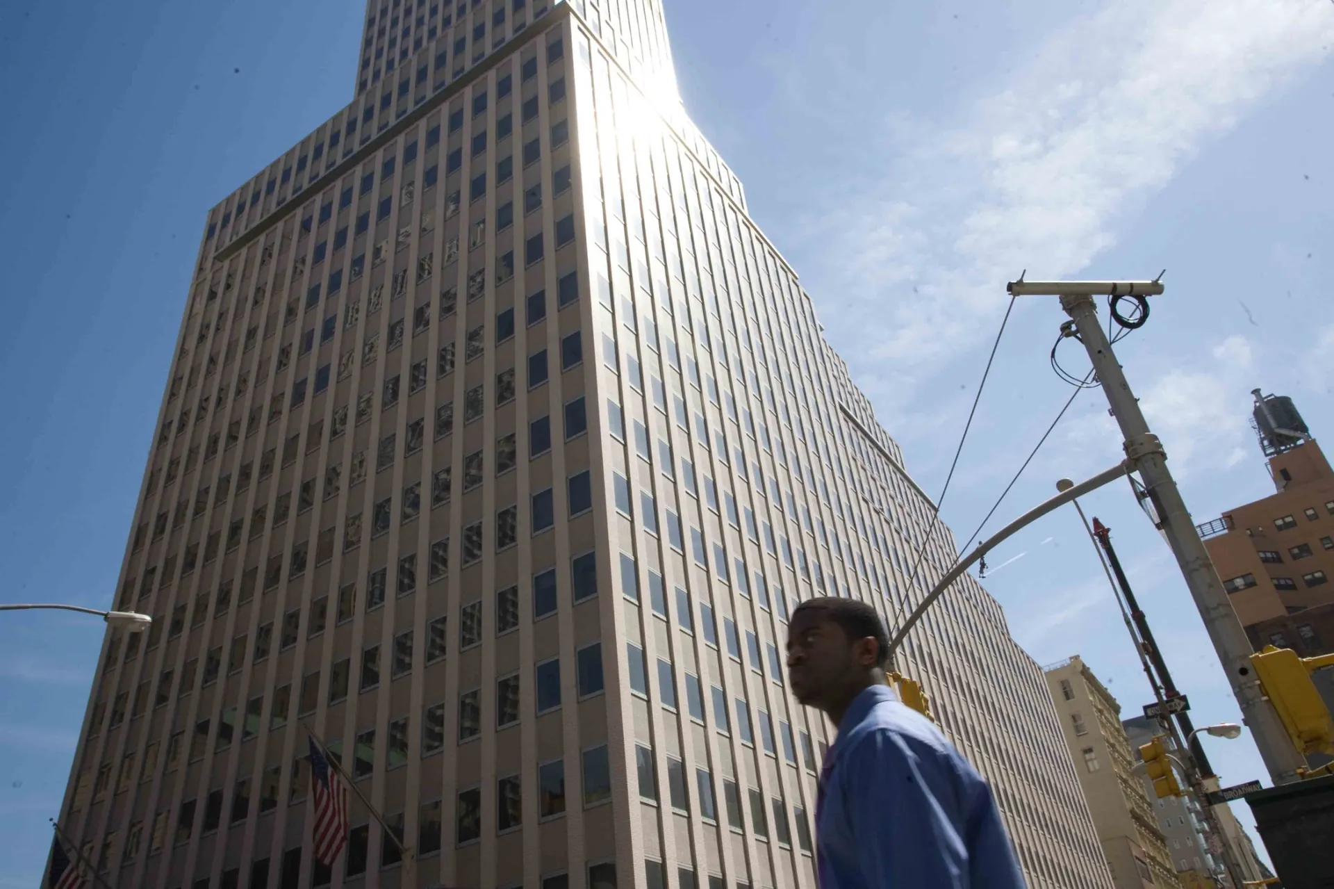 Passant au pied d'un gratte-ciel Art déco de Manhattan, contre-jour éblouissant